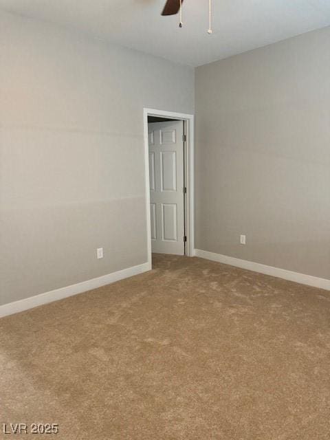 empty room featuring ceiling fan, light colored carpet, and baseboards