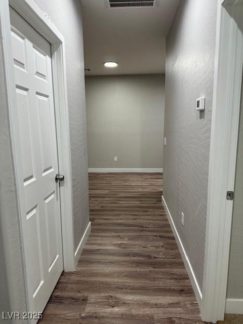 hallway featuring baseboards, wood finished floors, and visible vents