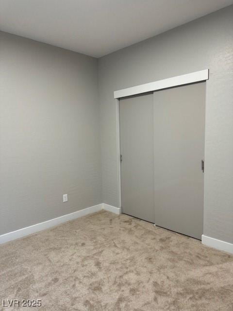 unfurnished bedroom featuring light colored carpet, baseboards, and a closet