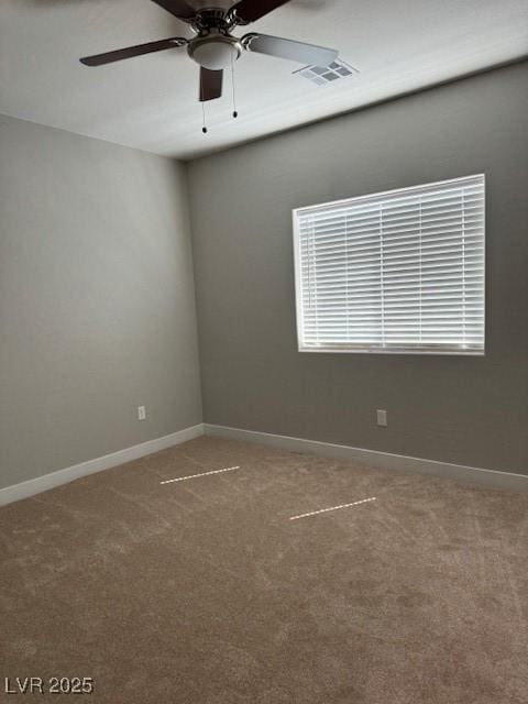 carpeted empty room with baseboards, a ceiling fan, and visible vents