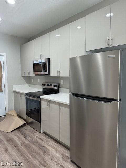 kitchen featuring light wood-type flooring, light countertops, white cabinetry, recessed lighting, and stainless steel appliances