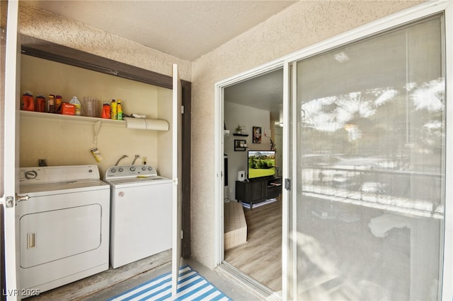 clothes washing area with a textured ceiling, washing machine and dryer, laundry area, and light wood-style floors