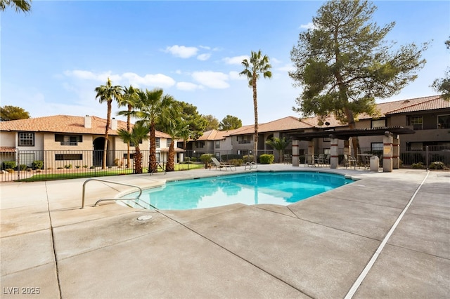 community pool featuring fence, a residential view, and a patio area