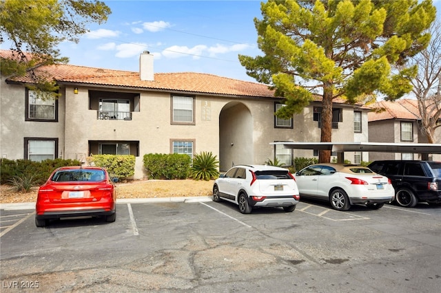 view of property featuring covered and uncovered parking