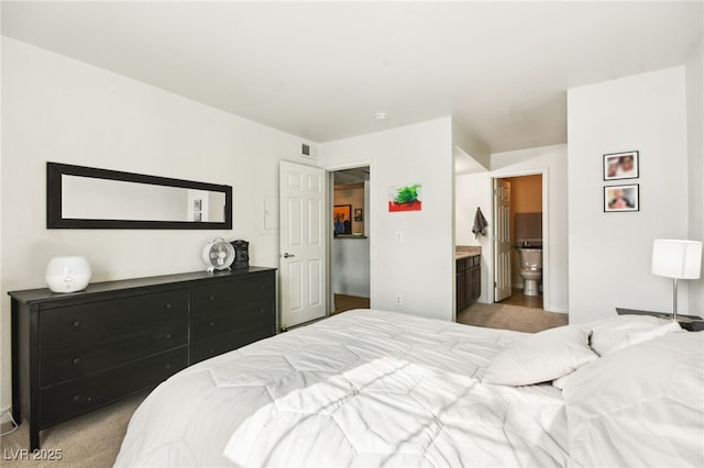 bedroom with light colored carpet, visible vents, and ensuite bath