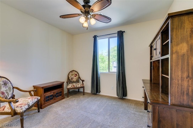sitting room featuring ceiling fan, light colored carpet, and baseboards
