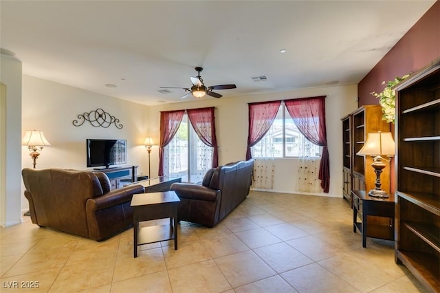 living area with visible vents, a ceiling fan, baseboards, and light tile patterned flooring