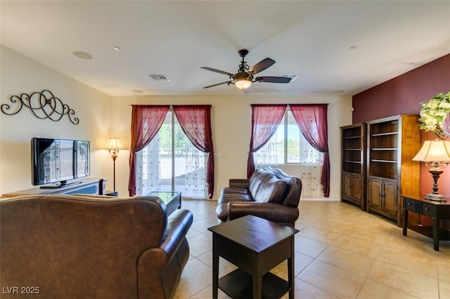 living area featuring visible vents, a ceiling fan, light tile patterned floors, and a healthy amount of sunlight