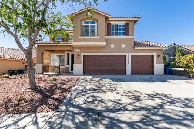 mediterranean / spanish home featuring an attached garage, stucco siding, a tiled roof, and concrete driveway