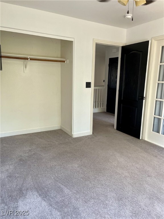 unfurnished bedroom featuring carpet floors, ceiling fan, baseboards, and a closet