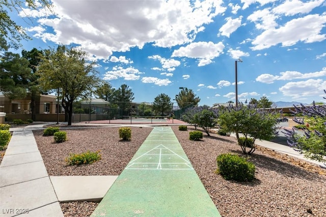 view of property's community featuring shuffleboard, a tennis court, and fence