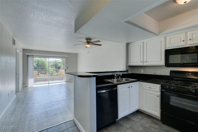 kitchen featuring dark countertops, ceiling fan, a sink, a peninsula, and black appliances