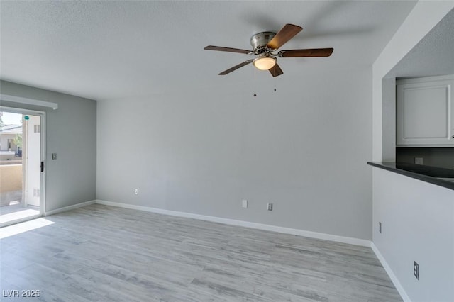 unfurnished living room featuring light wood-type flooring, a ceiling fan, and baseboards