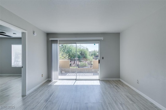 spare room featuring baseboards, ceiling fan, and wood finished floors