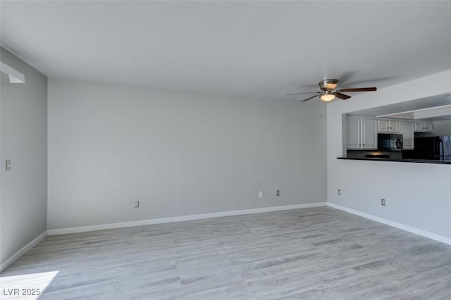 unfurnished living room with ceiling fan, baseboards, and light wood-style floors