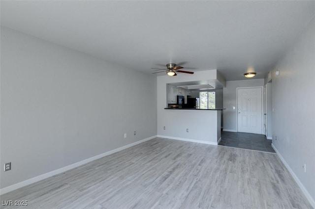 unfurnished living room with baseboards, a ceiling fan, and wood finished floors
