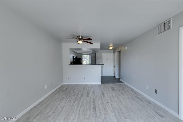 unfurnished living room featuring visible vents, baseboards, ceiling fan, and wood finished floors