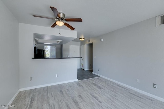 unfurnished living room featuring a ceiling fan, baseboards, visible vents, and wood finished floors