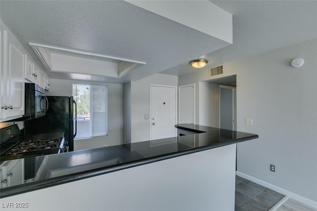 kitchen featuring dark countertops, white cabinetry, a peninsula, visible vents, and black appliances