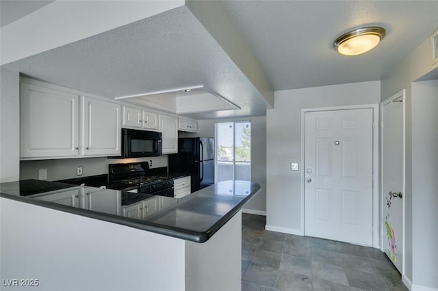 kitchen with a peninsula, dark countertops, baseboards, white cabinetry, and black appliances