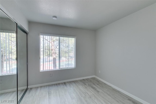unfurnished room with plenty of natural light, light wood-style flooring, and baseboards