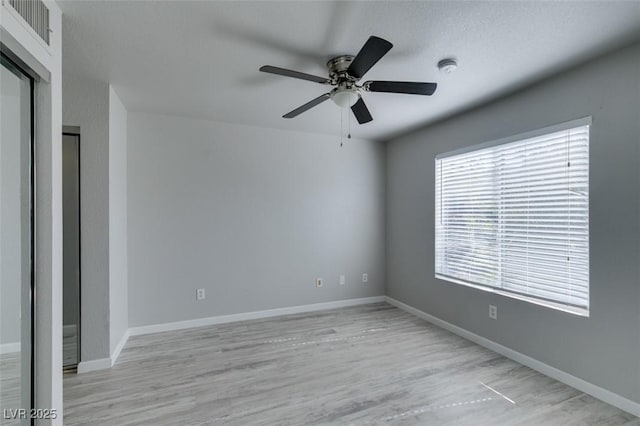 spare room with ceiling fan, visible vents, baseboards, and light wood-style floors