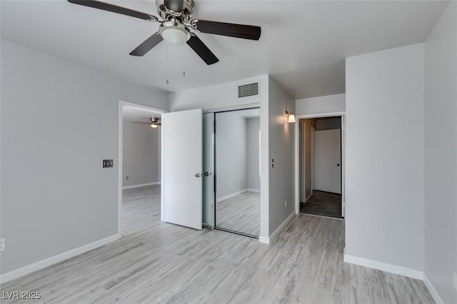 unfurnished bedroom with a ceiling fan, visible vents, wood finished floors, baseboards, and a closet
