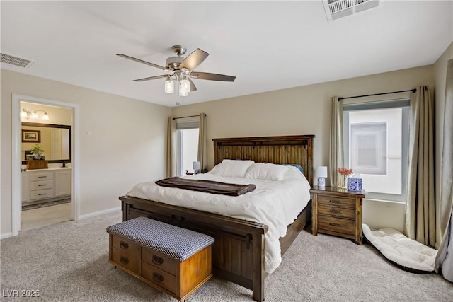bedroom featuring baseboards, light carpet, ensuite bath, and visible vents