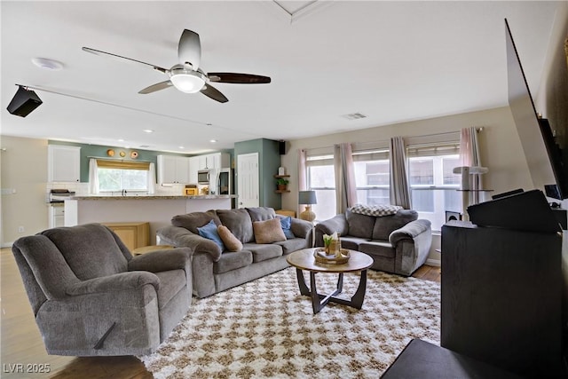 living area featuring visible vents, a ceiling fan, and light wood finished floors
