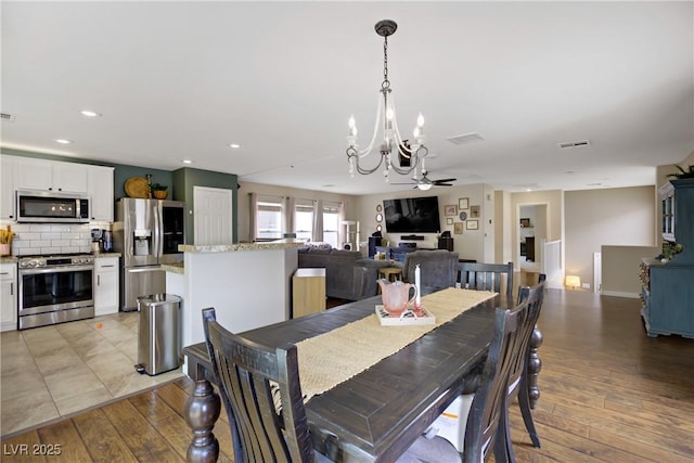 dining space with light wood-style floors, ceiling fan with notable chandelier, recessed lighting, and visible vents