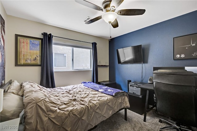 carpeted bedroom featuring visible vents, a textured wall, and ceiling fan