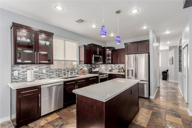 kitchen featuring appliances with stainless steel finishes, a sink, decorative backsplash, visible vents, and stone tile flooring
