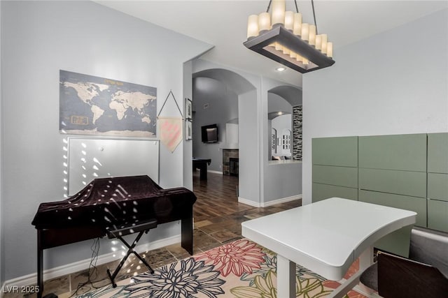 interior space with baseboards, arched walkways, and a fireplace