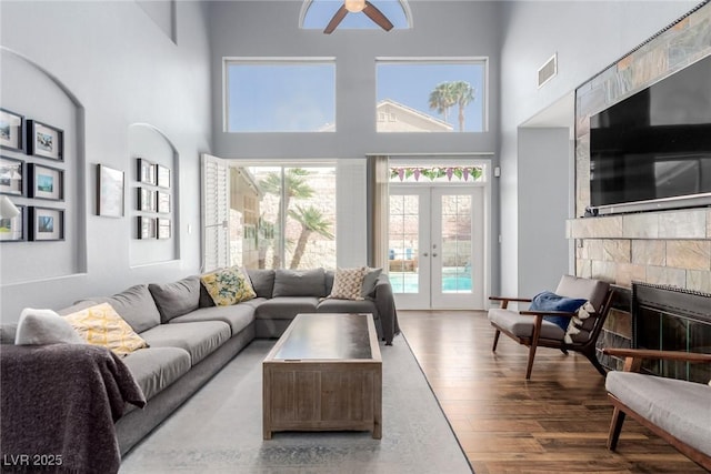living room with visible vents, wood finished floors, a high ceiling, french doors, and a ceiling fan