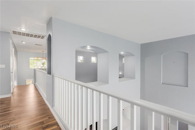 corridor featuring arched walkways, wood finished floors, and visible vents