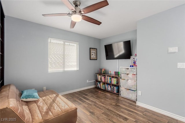 living area with a ceiling fan, baseboards, and wood finished floors