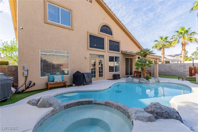 view of swimming pool featuring a pool with connected hot tub, french doors, a fenced backyard, and a grill