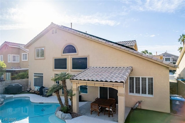 back of house featuring fence, stucco siding, a fenced in pool, a patio area, and a tiled roof
