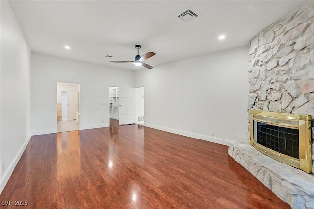 unfurnished living room featuring ceiling fan, a stone fireplace, recessed lighting, wood finished floors, and visible vents