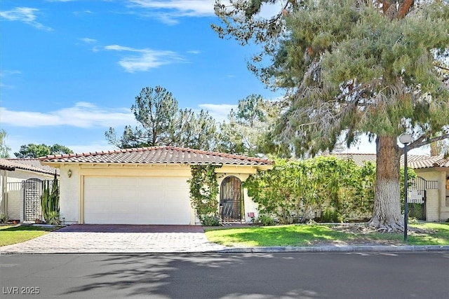 mediterranean / spanish home with an attached garage, decorative driveway, stucco siding, and a tiled roof