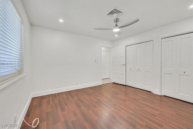 unfurnished bedroom featuring recessed lighting, multiple closets, visible vents, and wood finished floors