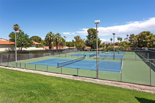 view of tennis court with fence and a yard