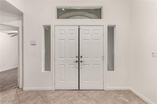 foyer featuring baseboards and light tile patterned flooring