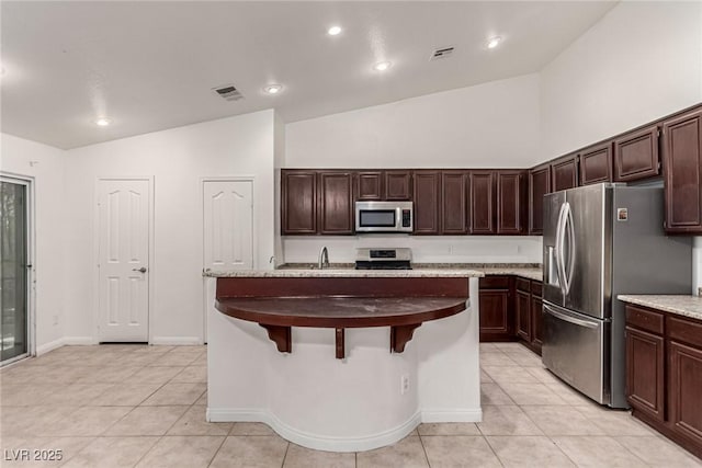 kitchen with dark brown cabinets, appliances with stainless steel finishes, light tile patterned floors, and visible vents