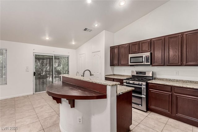 kitchen with visible vents, a center island with sink, light tile patterned floors, vaulted ceiling, and stainless steel appliances