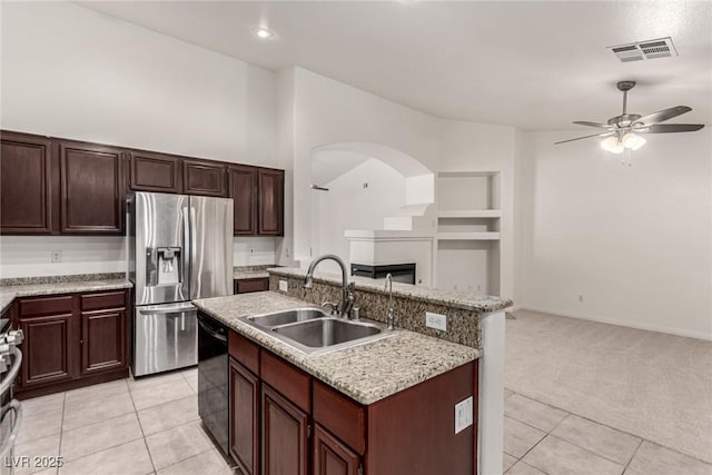 kitchen featuring a ceiling fan, open floor plan, black dishwasher, stainless steel fridge, and a sink
