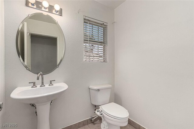 bathroom featuring tile patterned floors, baseboards, and toilet