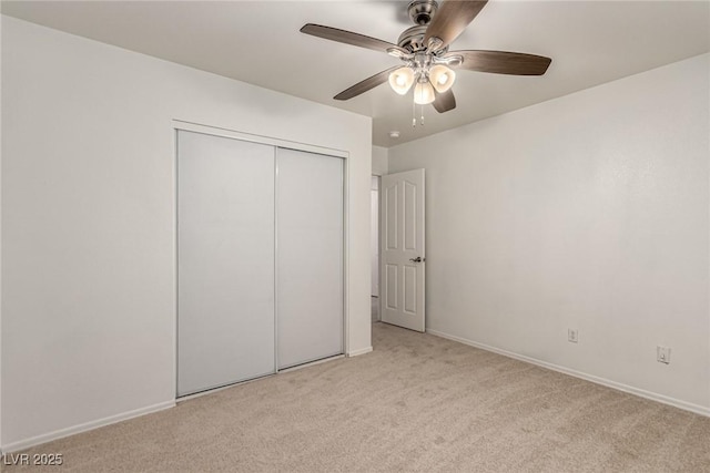 unfurnished bedroom featuring a closet, a ceiling fan, baseboards, and light carpet