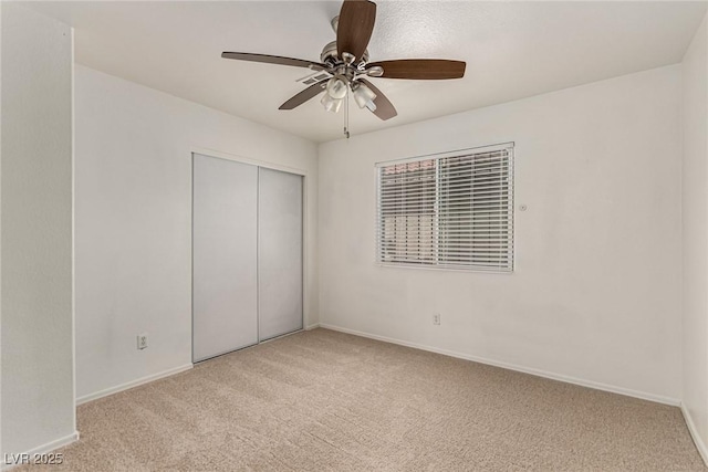 unfurnished bedroom featuring baseboards, ceiling fan, a closet, and light colored carpet