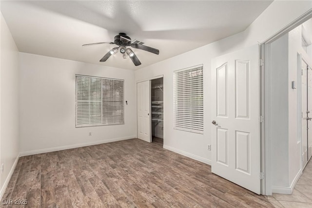 unfurnished bedroom with baseboards, light wood-style floors, ceiling fan, and a closet